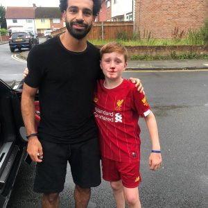 Mohamed Salah poses with young fan who ran into lamp post trying to get a wave