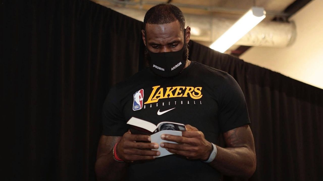 LeBron James walks down the tunnel reading a book, citing his enjoyment of reading. Mandatory Credit: Imagn Images