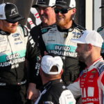 Sep 15, 2024; Watkins Glen, New York, USA; NASCAR Cup Series driver Chris Buescher (center) is congratulated by second place finisher driver Shane Van Gisbergen (right) in victory lane after winning the Go Bowling at The Glen at Watkins Glen International. Mandatory Credit: Matthew O'Haren-Imagn Images