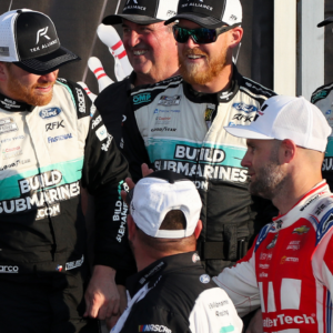 Sep 15, 2024; Watkins Glen, New York, USA; NASCAR Cup Series driver Chris Buescher (center) is congratulated by second place finisher driver Shane Van Gisbergen (right) in victory lane after winning the Go Bowling at The Glen at Watkins Glen International. Mandatory Credit: Matthew O'Haren-Imagn Images
