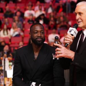Miami Heat president Pat Riley (R) shows former player Dwayne Wade (L) a bobble head while announcing that a statue in the likeness of Wade will be erected outside the arena in 2025, during halftime of the game between the Miami Heat and the Charlotte Hornets at Kaseya Center.