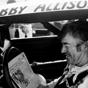 The defending Winston Cup points champion Bobby Allison checks out the newspaper during qualifying trials for the Nashville Pepsi 420 NASCAR Grand National race at Nashville International Raceway on July 13, 1984