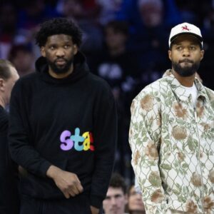 Injured Philadelphia 76ers Paul George (R) and Joel Embiid (L) look on during the first quarter against the Memphis Grizzlies at Wells Fargo Center.