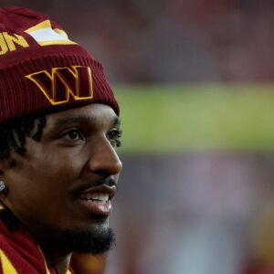Injured Washington Commanders quarterback Jayden Daniels looks on from the sidelines against the Carolina Panthers during the third quarter at Northwest Stadium.