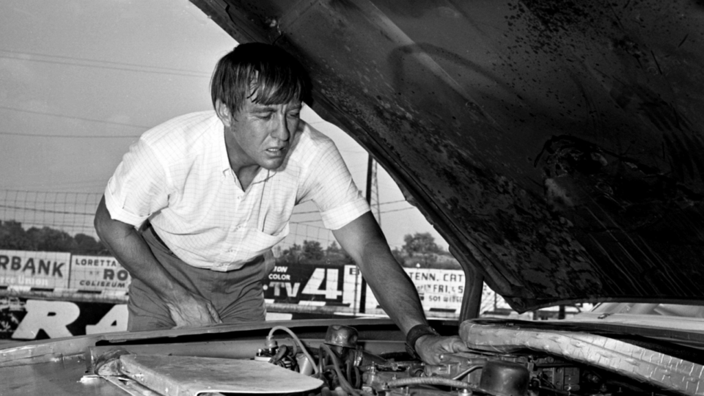 Driver Bobby Isaac makes sure everything is in good working order under the hood of his 1969 Dodge Charger before driving in the NASCAR 400 at Fairgrounds Speedway July 26, 1969. Isaac was second fastest qualifier. Title 1969 Auto Racing