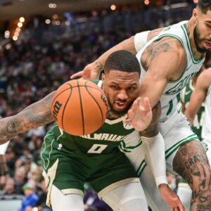 Milwaukee Bucks guard Damian Lillard (0) and Boston Celtics forward Jayson Tatum (0) reach for a loose ball in the second quarter at Fiserv Forum.