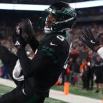Oct 31, 2024; East Rutherford, New Jersey, USA; New York Jets wide receiver Garrett Wilson (5) catches a touchdown pass while being defended by Houston Texans cornerback Kamari Lassiter (4) during the second half at MetLife Stadium.
