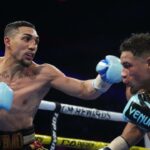 Teofimo Lopez (black/gold/red trunks) and Jamaine Ortiz (black trunks) box during their WBO Junior Welterweight World Title bout at Michelob ULTRA Arena.