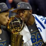 Golden State Warriors guard Stephen Curry (30) poses with the Larry O'Brien Trophy as Golden State Warriors guard Andre Iguodala (9) celebrates with the NBA Finals MVP trophy after beating the Cleveland Cavaliers in game six of the NBA Finals at Quicken Loans Arena