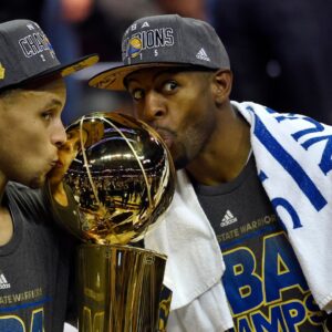Golden State Warriors guard Stephen Curry (30) poses with the Larry O'Brien Trophy as Golden State Warriors guard Andre Iguodala (9) celebrates with the NBA Finals MVP trophy after beating the Cleveland Cavaliers in game six of the NBA Finals at Quicken Loans Arena