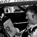 The defending Winston Cup points champion Bobby Allison checks out the newspaper during qualifying trials for the Nashville Pepsi 420 NASCAR Grand National race at Nashville International Raceway on July 13, 1984
