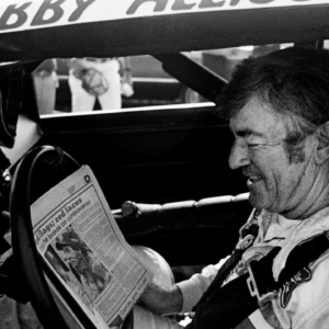 The defending Winston Cup points champion Bobby Allison checks out the newspaper during qualifying trials for the Nashville Pepsi 420 NASCAR Grand National race at Nashville International Raceway on July 13, 1984