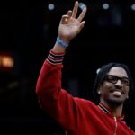 Washington Commanders quarter back Jayden Daniels waves to the crowd from courtside during a timeout in the game between the Washington Wizards and Golden State Warriors in the first half at Capital One Arena.