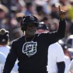 Colorado Buffaloes head coach Deion Sanders calls in a play in the first quarter against the Utah Utes at Folsom Field.