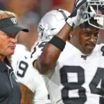 Oakland Raiders wide receiver Antonio Brown (84) puts on bis football helmet alongside head coach Jon Gruden against the Arizona Cardinals during a preseason game at State Farm Stadium.