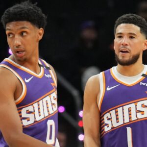 Phoenix Suns forward Ryan Dunn (0) and Phoenix Suns guard Devin Booker (1) look on against the Miami Heat during the first half at Footprint Center.