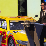 NASCAR Cup Series driver Joey Logano (22) next to his car and trophy talks to the audience after being announced as the three time Cup champion during the NASCAR Awards Banquet at Charlotte Convention Center.