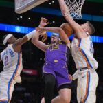 Los Angeles Lakers guard Austin Reaves (15) shoots the ball against Oklahoma City Thunder guard Shai Gilgeous-Alexander (2) and center Isaiah Hartenstein (55) in the first half at Crypto.com Arena.