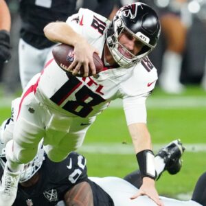Dec 16, 2024; Paradise, Nevada, USA; Atlanta Falcons quarterback Kirk Cousins (18) is tripped up by Las Vegas Raiders defensive tackle Jonah Laulu (96) during the second quarter at Allegiant Stadium.