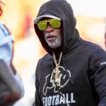 Colorado head coach Deion Sanders watches his players warmup prior to the game between the Kansas Jayhawks and the Colorado Buffaloes at GEHA Field at Arrowhead Stadium.