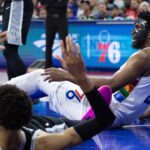 Philadelphia 76ers center Joel Embiid (21) and San Antonio Spurs center Victor Wembanyama (1) fall to the floor after colliding during the second quarter at Wells Fargo Center.