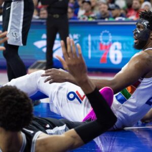 Philadelphia 76ers center Joel Embiid (21) and San Antonio Spurs center Victor Wembanyama (1) fall to the floor after colliding during the second quarter at Wells Fargo Center.