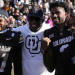 Colorado Buffaloes safety Shilo Sanders (21) and head coach Deion Sanders and quarterback Shedeur Sanders (2) and social media producer Deion Sanders Jr. following the win against the Oklahoma State Cowboys at Folsom Field.