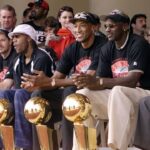 Chicago Bulls with their six championship trophies. Left to right in the front row are Luc Longley, Toni Kukoc, Ron Harper, Dennis Rodman (leaning back), Scottie Pippen, Michael Jordan and Chicago Mayor Richard Daley at a championship rally at Grant Park in Chicago.