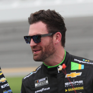 Corey LaJoie talks with crew members while he waits to qualify, Friday, February 16, 2024, for the Fresh From Florida 250 at Daytona International Speedway.