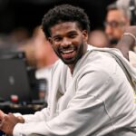 Colorado Buffaloes quarterback Shedeur Sanders laughs as he watches the game between the Dallas Mavericks and the Denver Nuggets during the second half at the American Airlines Center.