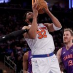 New York Knicks center Karl-Anthony Towns (32) is fouled by Toronto Raptors guard RJ Barrett (9) as he drives to the basket against Raptors center Jakob Poeltl (19) during the third quarter at Madison Square Garden.