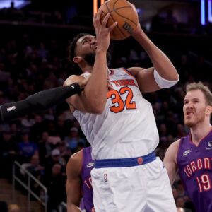 New York Knicks center Karl-Anthony Towns (32) is fouled by Toronto Raptors guard RJ Barrett (9) as he drives to the basket against Raptors center Jakob Poeltl (19) during the third quarter at Madison Square Garden.