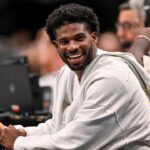 Colorado Buffaloes quarterback Shedeur Sanders laughs as he watches the game between the Dallas Mavericks and the Denver Nuggets during the second half at the American Airlines Center.