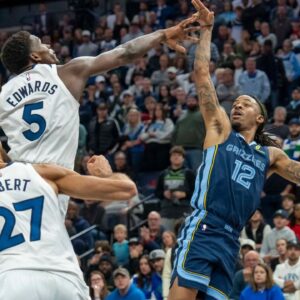 Memphis Grizzlies guard Ja Morant (12) falls back after releasing the game winning shot over Minnesota Timberwolves guard Anthony Edwards (5) in the second half at Target Center.