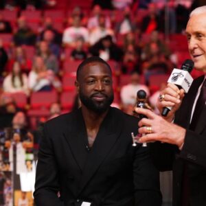Miami Heat president Pat Riley (R) shows former player Dwayne Wade (L) a bobble head while announcing that a statue in the likeness of Wade will be erected outside the arena in 2025, during halftime of the game between the Miami Heat and the Charlotte Hornets at Kaseya Center.
