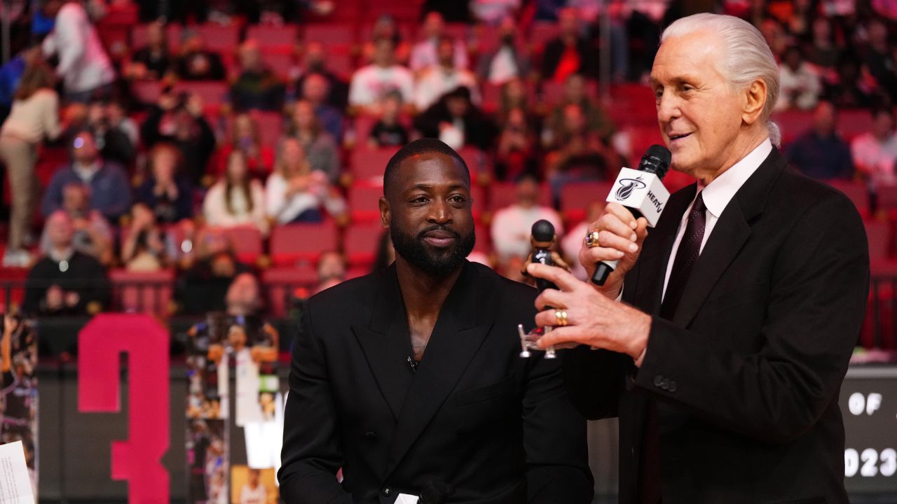Miami Heat president Pat Riley (R) shows former player Dwayne Wade (L) a bobble head while announcing that a statue in the likeness of Wade will be erected outside the arena in 2025, during halftime of the game between the Miami Heat and the Charlotte Hornets at Kaseya Center.