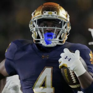 Notre Dame Fighting Irish running back Jeremiyah Love (4) scores a touchdown while being chased by Indiana Hoosiers defensive back D'Angelo Ponds (5) and Indiana Hoosiers defensive back Jamari Sharpe (22) during the first half of a game between the Indiana Hoosiers and the Notre Dame Fighting Irish in first round of the College Football Playoff on Friday, Dec. 20, 2024, in South Bend.