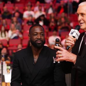 Miami Heat president Pat Riley (R) shows former player Dwayne Wade (L) a bobble head while announcing that a statue in the likeness of Wade will be erected outside the arena in 2025, during halftime of the game between the Miami Heat and the Charlotte Hornets at Kaseya Center