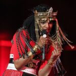 Recording artist MIA gestures towards the camera during the halftime show for Super Bowl XLVI between the New York Giants and New England Patriots at Lucas Oil Stadium.
