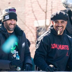 Philadelphia Eagles owner, Jeffrey Lurie, left, joins head coach Nick Sirianni and quarterback Jalen Hurts atop one of the team buses during the Super Bowl 59 victory parade along S. Broad Street in Philadelphia, PA, on Friday, Feb. 14, 2025.