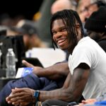 2024 Heisman Trophy winner Travis Hunter Jr. laughs during the second half of the game between the Dallas Mavericks and the Minnesota Timberwolves at the American Airlines Center.
