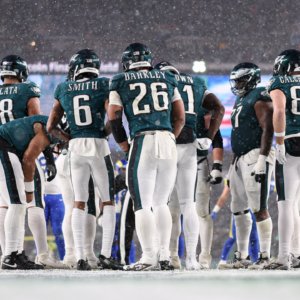 Philadelphia Eagles running back Saquon Barkley (26) and his team huddle up for a play against the Los Angeles Rams in a 2025 NFC divisional round game at Lincoln Financial Field.