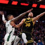Golden State Warriors guard Stephen Curry (30) shoots the ball while being defended by Milwaukee Bucks guard Damian Lillard (0) in the third quarter at the Chase Center.