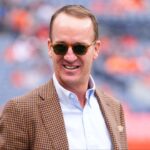 Retired NFL player Peyton Manning stands on the sidelines of Empower Field at Mile High before the game between the Carolina Panthers Denver Broncos.