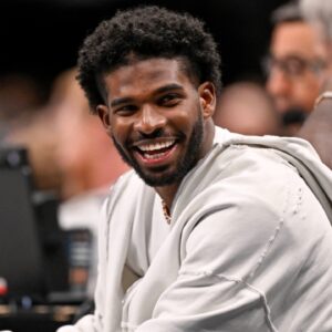Jan 14, 2025; Dallas, Texas, USA; Colorado Buffaloes quarterback Shedeur Sanders laughs as he watches the game between the Dallas Mavericks and the Denver Nuggets during the second half at the American Airlines Center.