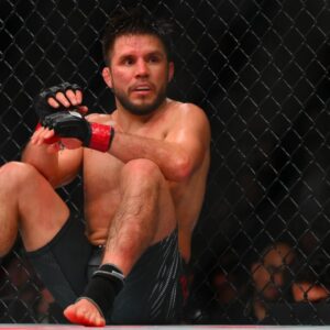 Henry Cejudo (red gloves) sits down after being poked in the eye by Song Yadong (blue gloves) in the bantamweight bout during UFC Fight Night at Climate Pledge Arena.