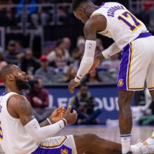 Los Angeles Lakers guard Dennis Schroder (17) helps up teammate Los Angeles Lakers forward LeBron James (6) during the second half of a game against the Detroit Pistons at Little Caesars Arena.