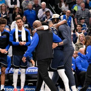Dallas Mavericks guard Kyrie Irving (11) is helped off the court by forward Anthony Davis (3) during the second quarter against the Sacramento Kings at the American Airlines Center.