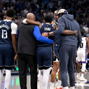 Dallas Mavericks guard Kyrie Irving (11) is helped off the court by forward Naji Marshall (13) and forward Anthony Davis (3) during the second quarter against the Sacramento Kings at the American Airlines Center.