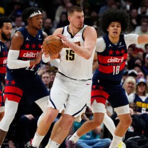 Washington Wizards forward Richaun Holmes (22) and forward Kyshawn George (18) defend on Denver Nuggets center Nikola Jokic (15) in the second half at Ball Arena